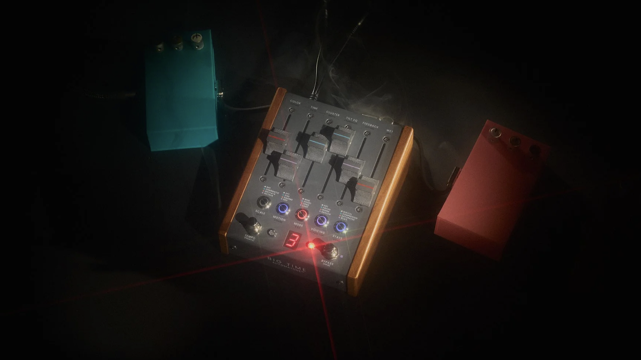Studio photo of a boutique stereo delay guitar pedal with wooden sides and multiple sliders, glowing LED indicators, and connected cables, surrounded by two smaller effects pedals in teal and red on a dark background with dramatic lighting.
